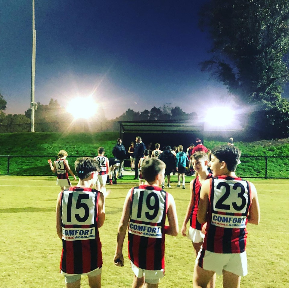4 young players talking in a  group with players and spectators behine